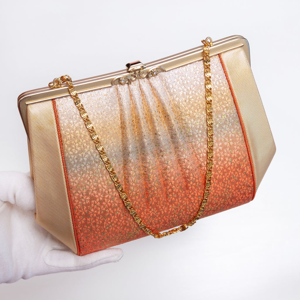 Sculptural Japanese silk clutch held at three-quarter view with gold-tone swirl-link chain extended