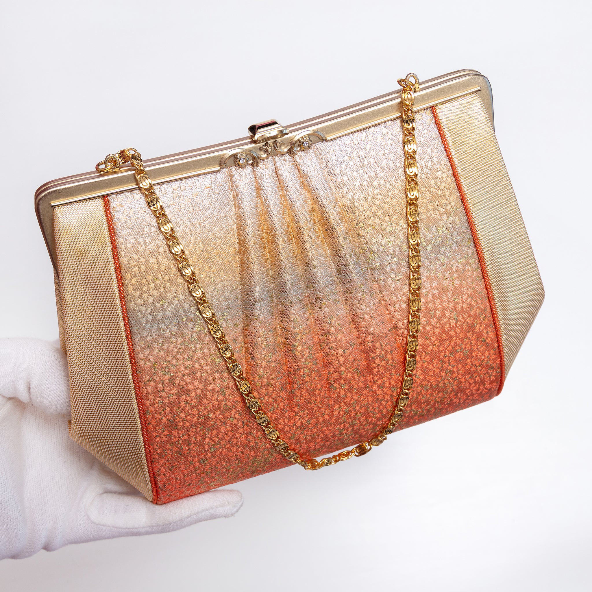 Sculptural Japanese silk clutch held at three-quarter view with gold-tone swirl-link chain extended