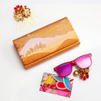 Metallic gold and bronze vintage clutch bag with landscape scene on a white background surrounded by accessories.