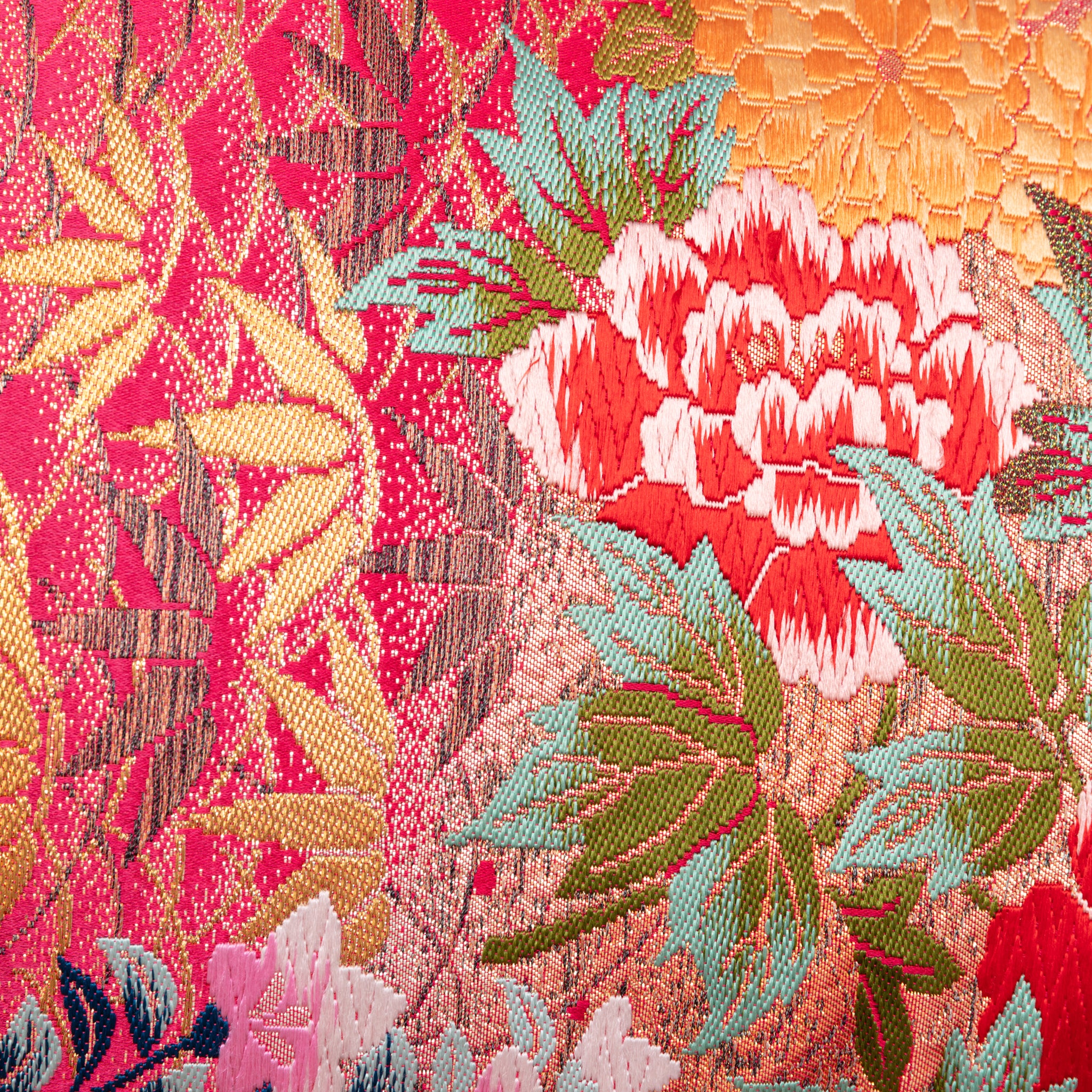 Close-up of the pink ombre fabric showcasing delicate crane and floral embroidery on purple velvet bolster cushion side