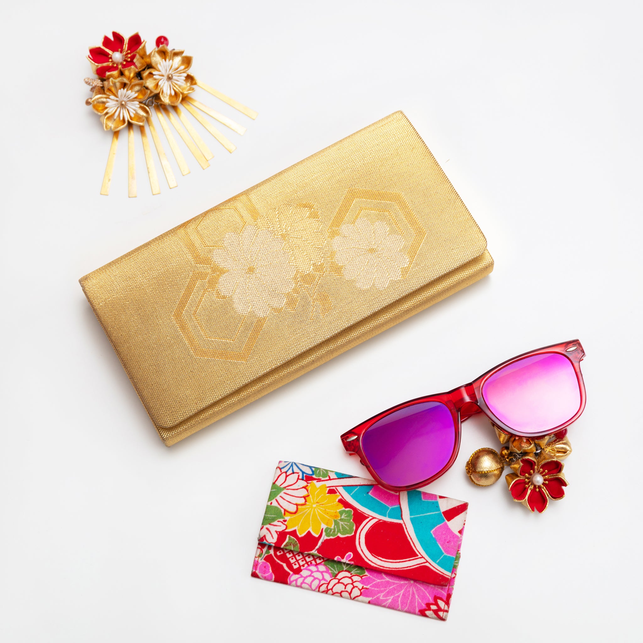 Vintage Japanese silk clutch bag with floral design on a white background with sunglasses and hairpin.