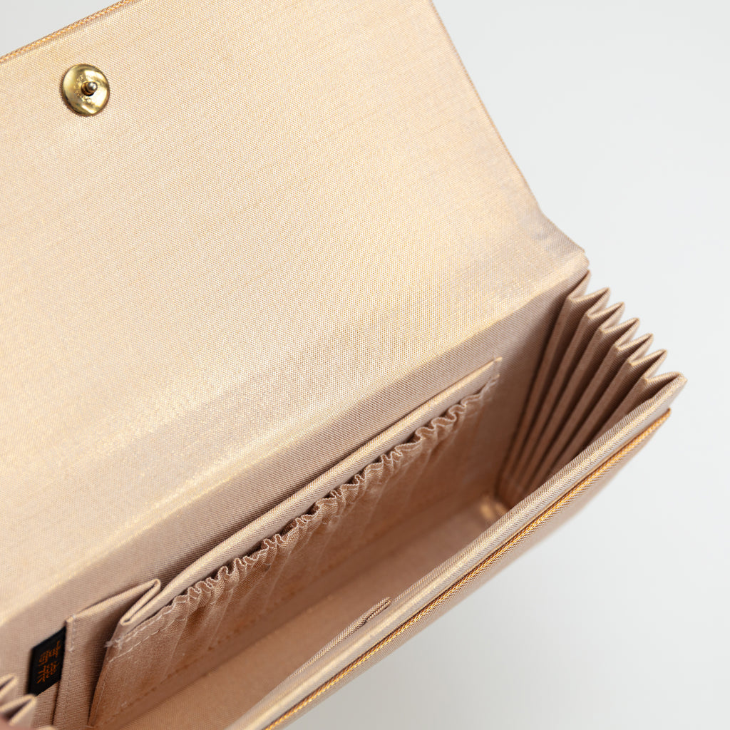 Interior view of a vintage gold silk clutch bag showing gold silk lining and interior pockets.