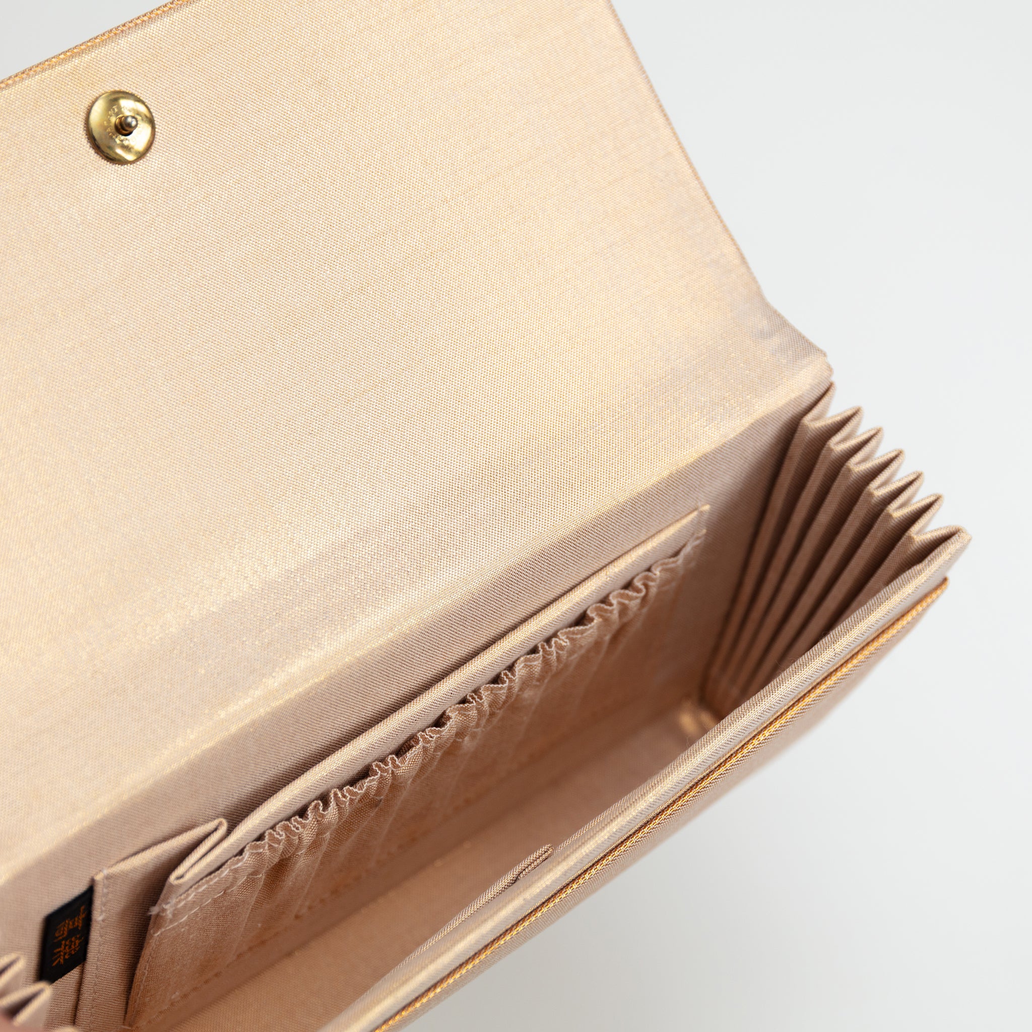 Interior view of a vintage gold silk clutch bag showing gold silk lining and interior pockets.