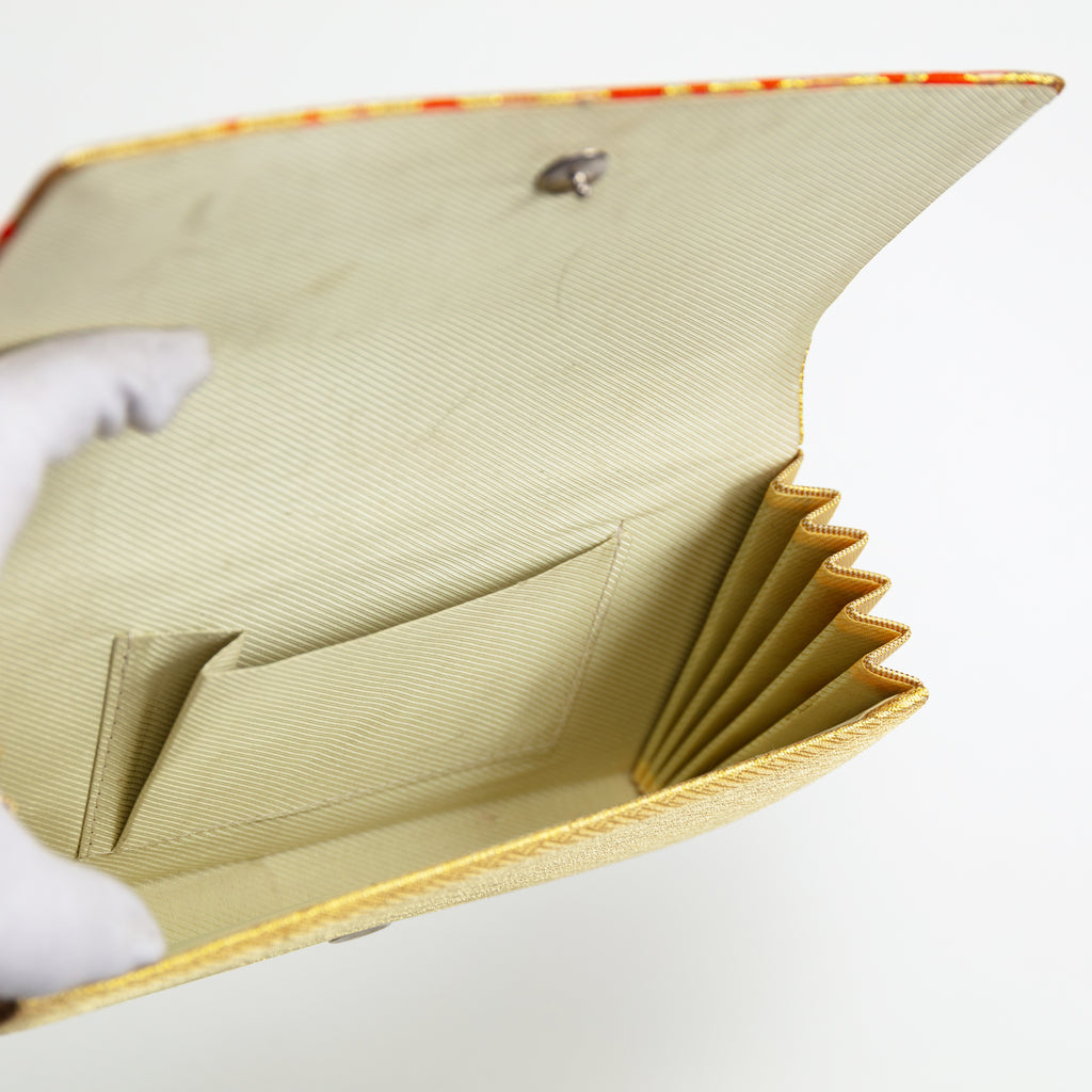 View of a vintage Japanese silk clutch bag held open by a gloved hand showing cream silk twill lining and internal pocket of the bag.