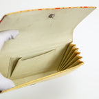 View of a vintage Japanese silk clutch bag held open by a gloved hand showing cream silk twill lining and internal pocket of the bag.