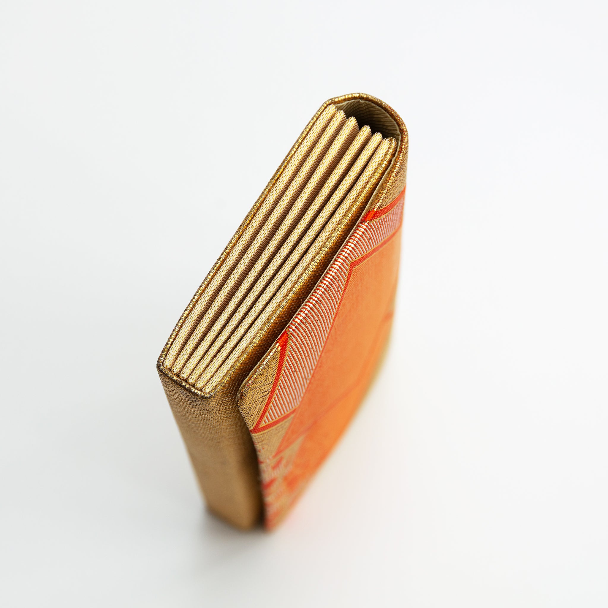 Side view of a vintage gold silk Japanese envelope clutch bag showing gold concertina style folded side panel.