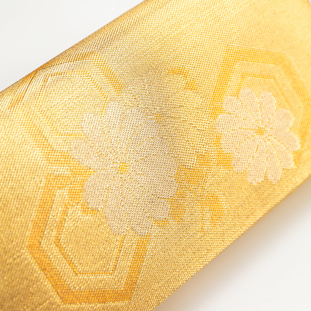 Close up of a vintage Japanese kimono silk clutch bag in metallic gold showing fortune hexagons and flowers.