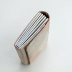 Side view of a vintage Japanese silk fold over clutch bag with silver concertina edge. On white.