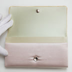 Interior view of a vintage Japanese pin clutch bag with cream silk lining, held open by gloved hand.