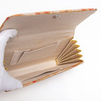 Open gold red clutch bag showing cream silk lining and interior pockets, some age spots.