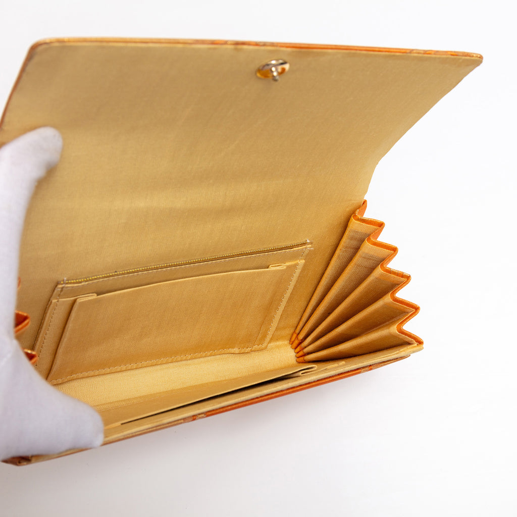 Open vintage Japanese clutch purse showing buttercream silk interior and stud fastening