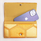 Gold kimono silk clutch bag shown with iPhone 14 Pro Max for scale