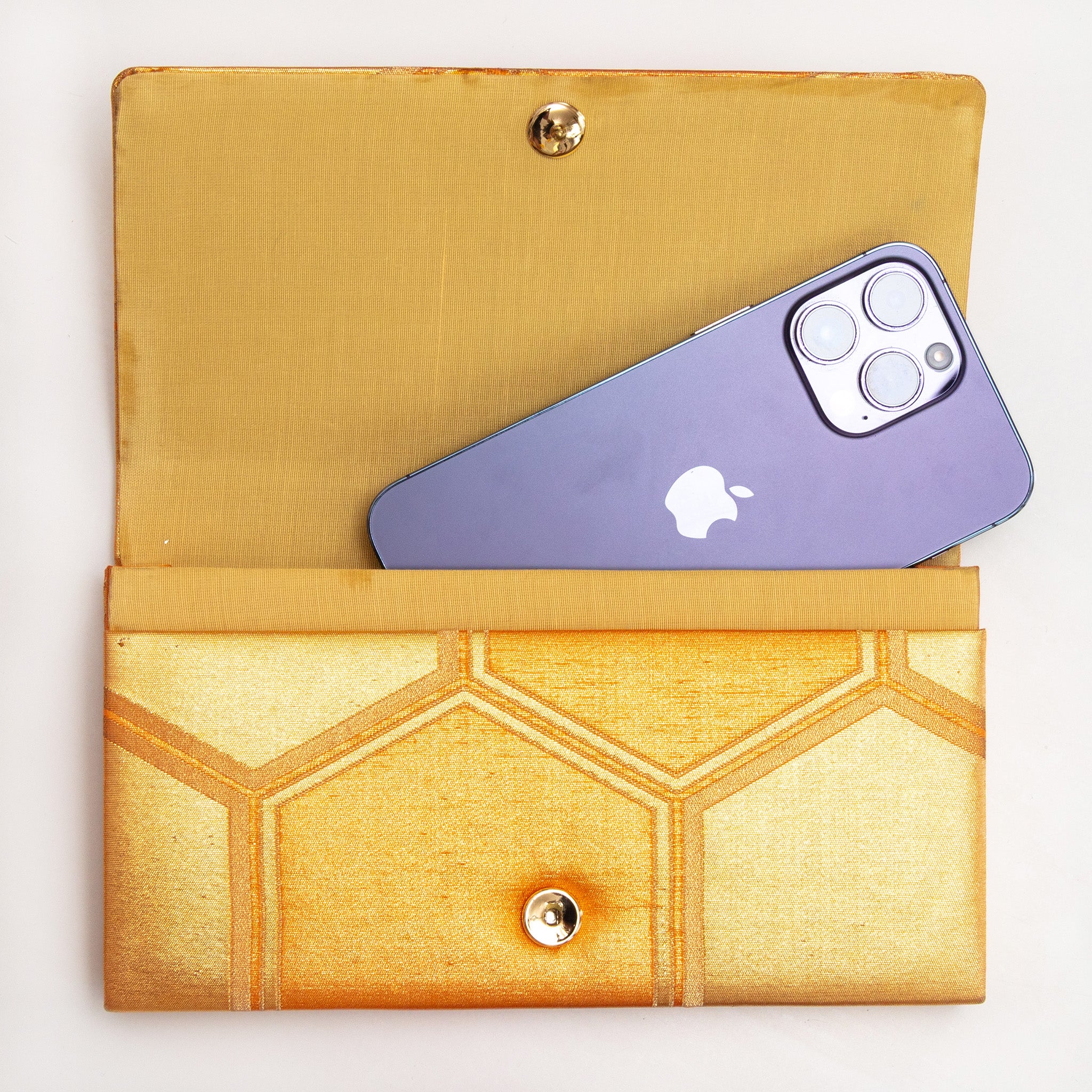 Gold kimono silk clutch bag shown with iPhone 14 Pro Max for scale