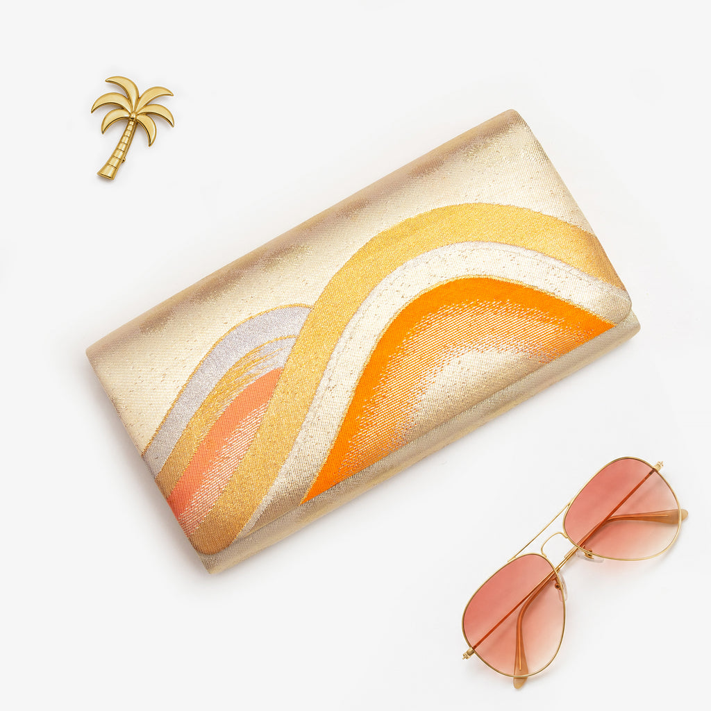 Gold orange vintage Japanese silk clutch bag styled with sunglasses and palm brooch