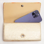 Gold orange kimono silk clutch bag shown with iPhone 14 Pro Max for scale