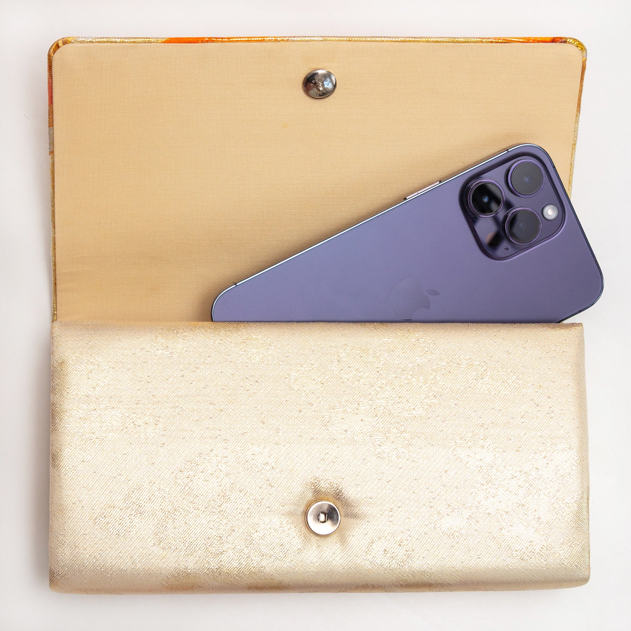 Gold orange kimono silk clutch bag shown with iPhone 14 Pro Max for scale
