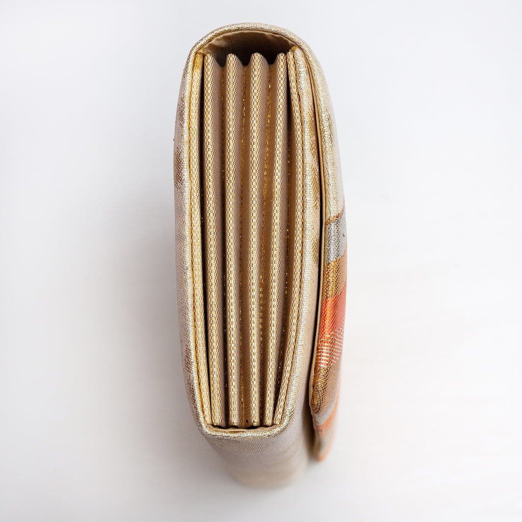 Side view of gold orange envelope clutch showing folded metallic gold concertina sides
