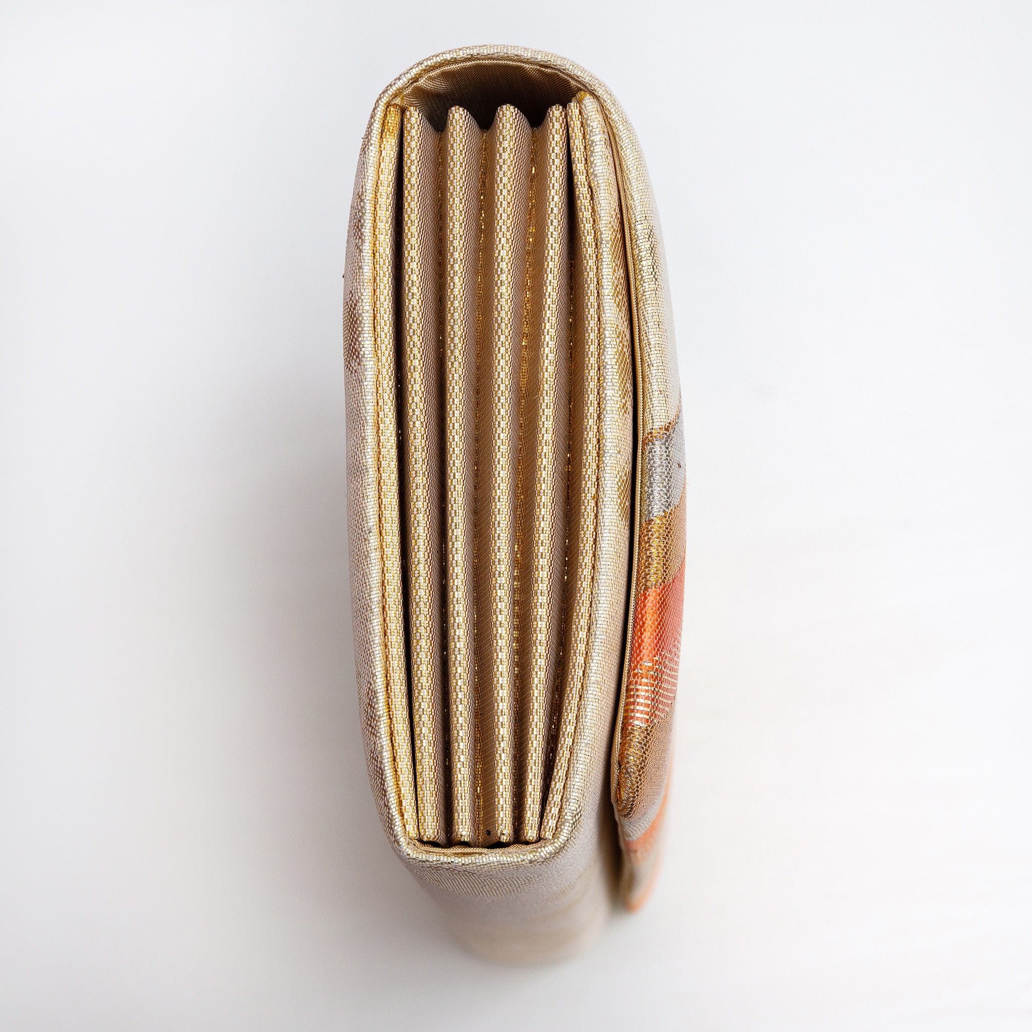 Side view of gold orange envelope clutch showing folded metallic gold concertina sides