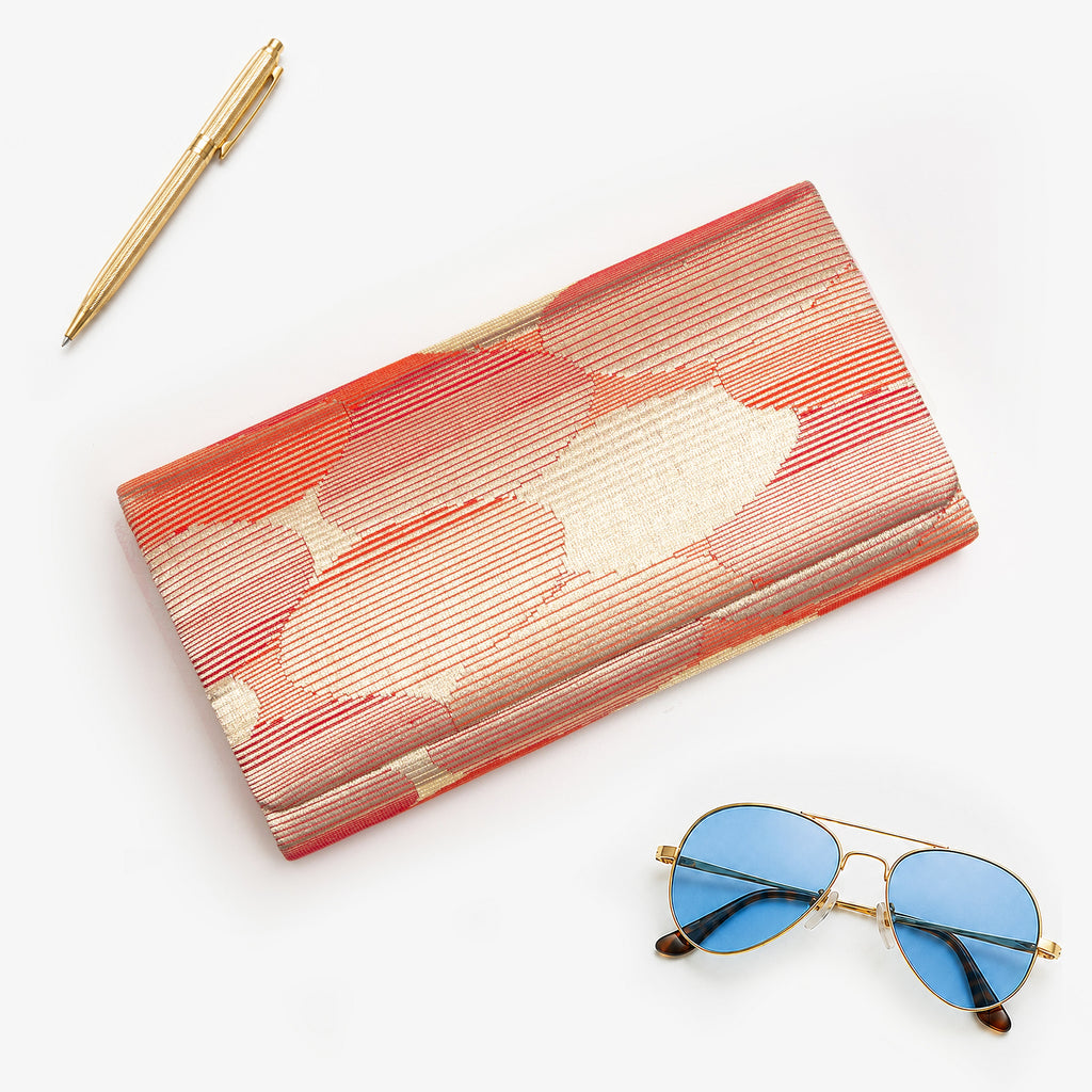 Red-gold vintage Japanese silk clutch bag, abstract cloud pattern, styled with sunglasses and gold pen