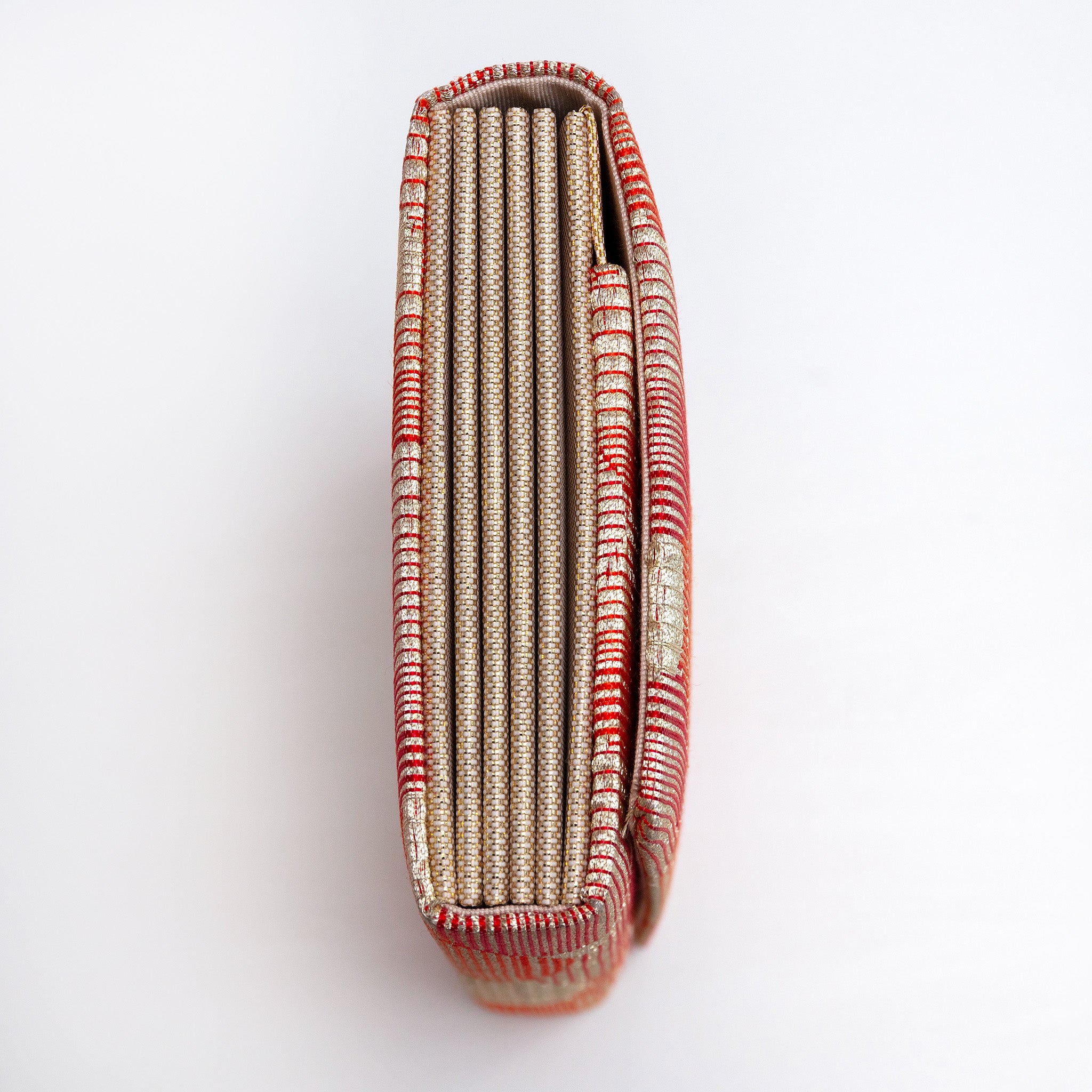 Side view of red-gold envelope clutch showing folded concertina sides in gold and cream silk.