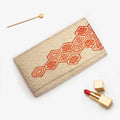 Gold vintage Japanese silk clutch bag with red Kikkō pattern, styled with lipstick and hairpin