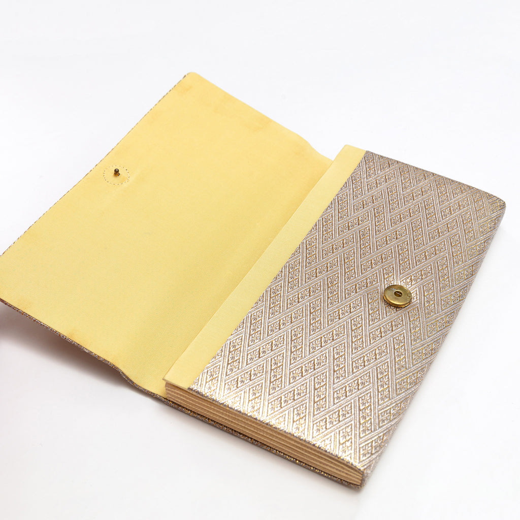 Open vintage Japanese clutch purse showing gold silk interior and snap fastening