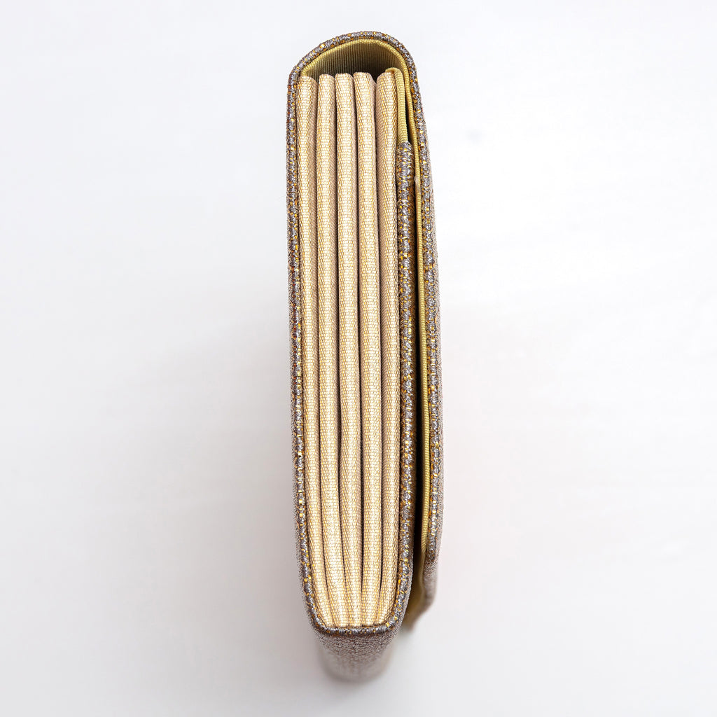 Side view of gold envelope clutch bag showing slim concertina folded sides