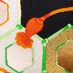 Close-up of gold and black geometric silk pattern highlighting intricate obi textile weave details and rich color contrast.
