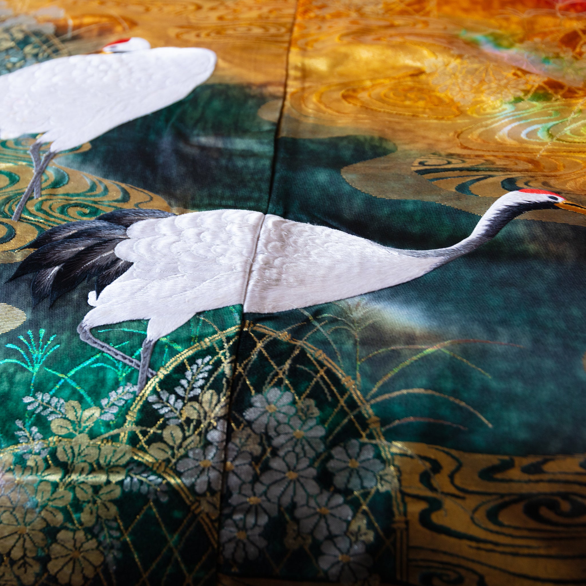 close up of vintage uchikake silk with white cranes over green and gold