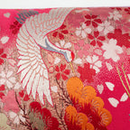 Close-up of the embroidered cranes and lilac velvet trim along the pillow's edge, showcasing detailed floral stitching and