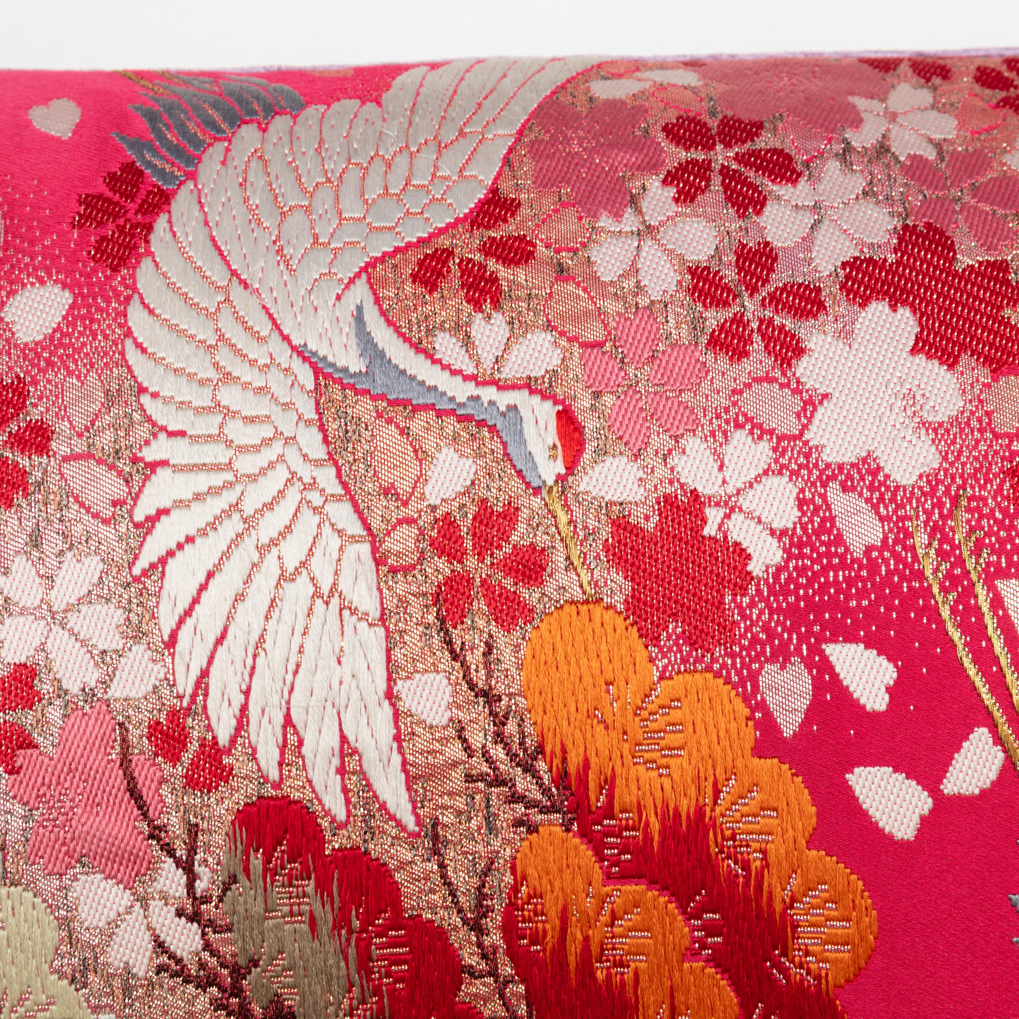 Close-up of the embroidered cranes and lilac velvet trim along the pillow's edge, showcasing detailed floral stitching and
