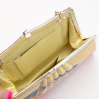 Vintage Japanese silk clutch bag held open by a hand showing the yellow silk lining and internal pockets.