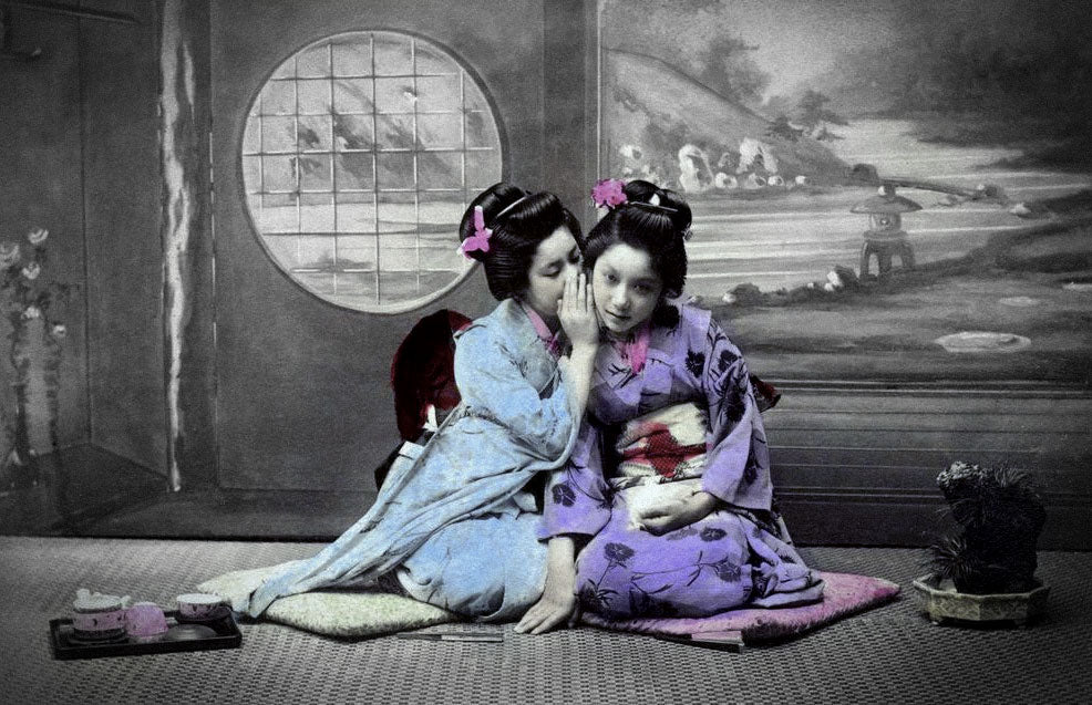 Vintage hand-tinted photograph of two Japanese women in kimono sharing conversation