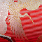 Close-up of the richly textured purple velvet backing and intricate silk crane embroidery on the pillow's edge detail.