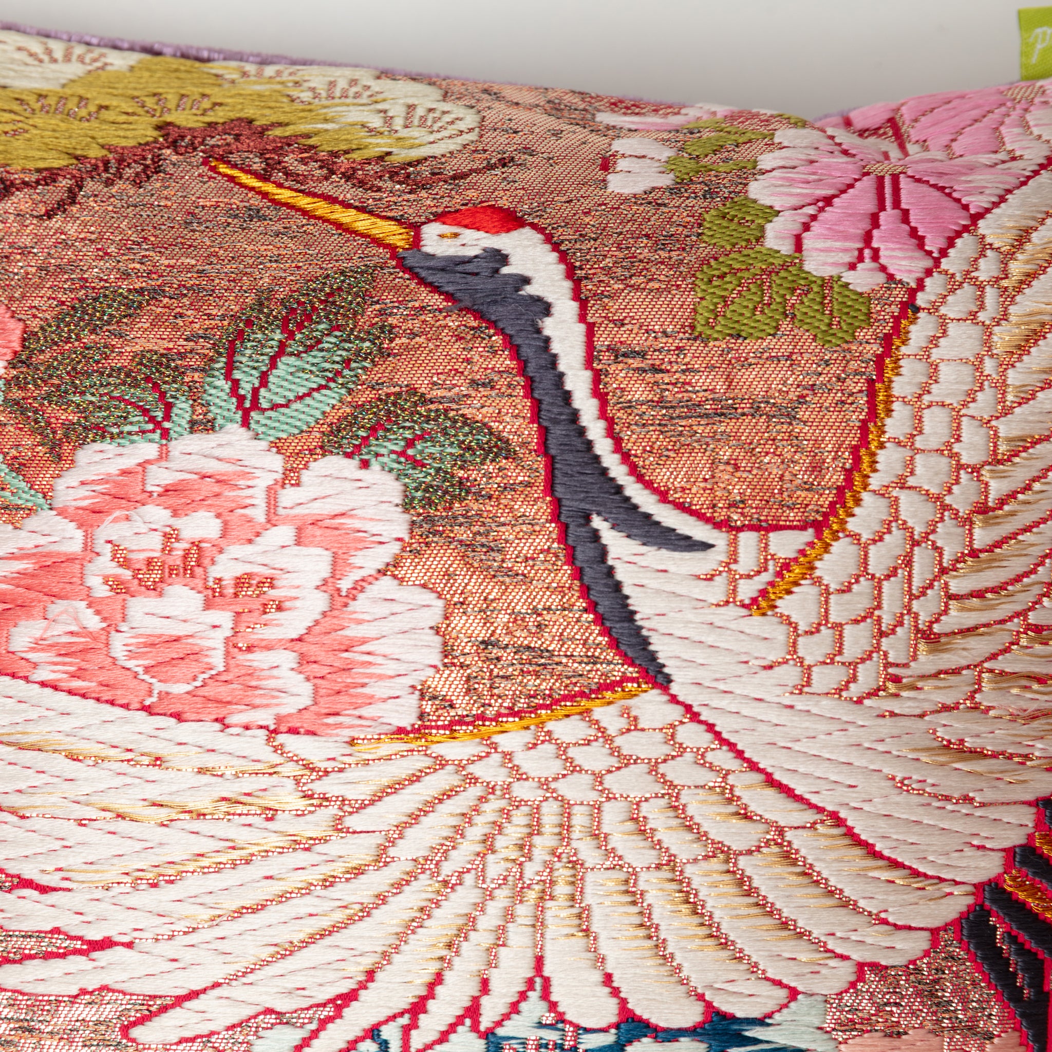 Close-up of the crimson fabric piping along the bolster's edge, highlighting the textured lilac velvet and intricate crane