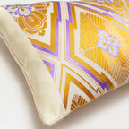 View of the side of the vintage Japanese oi cushion with cream silk border and purple and gold geometric pattern.