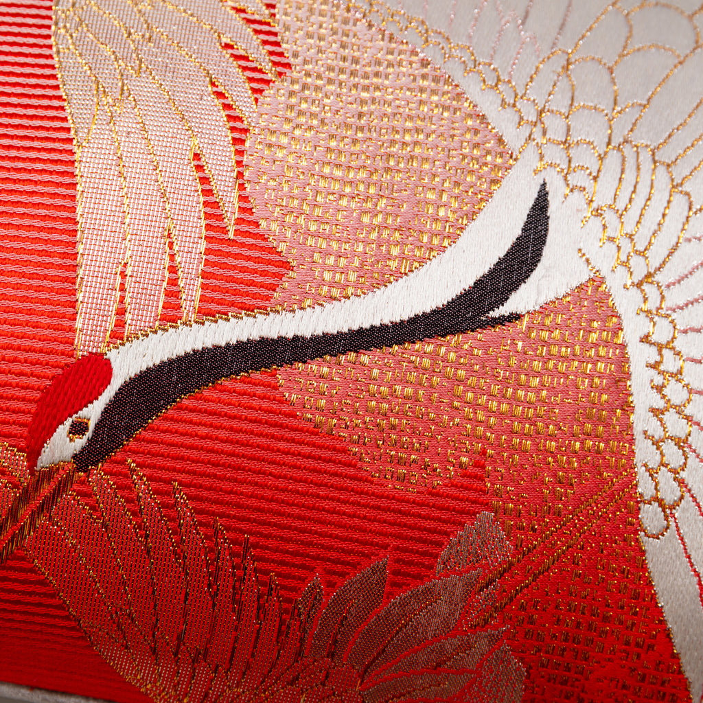 Close-up of the vibrant red silk fabric and taupe velvet trim detail on the bolster pillow's curved edge.