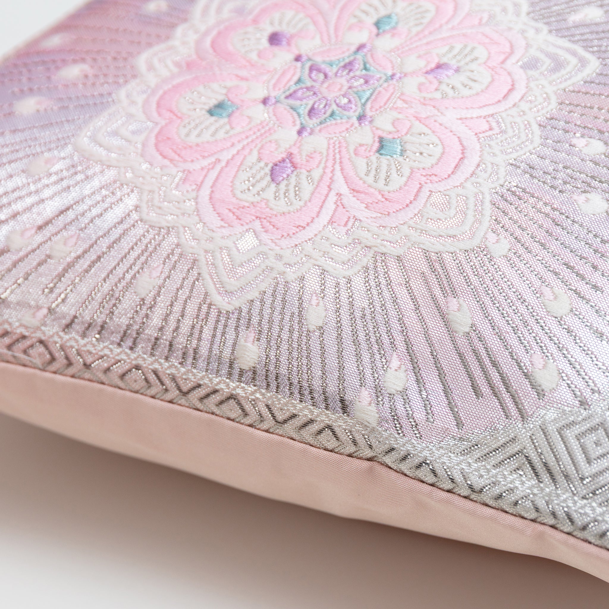 Detail of edge of obi cushion showing a silver border, pink flower motif and pink back.