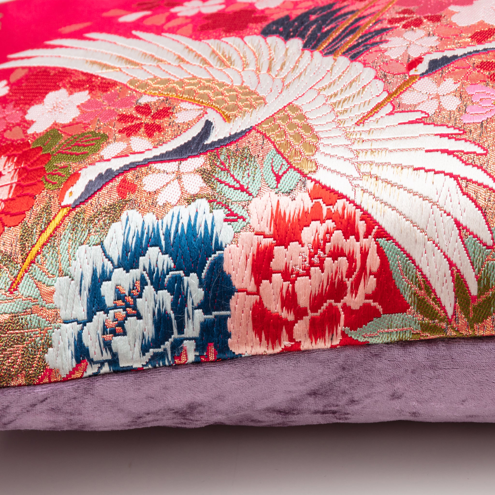 Close-up of the vibrant red silk fabric and detailed purple velvet embroidery on the Flying Cranes design of the bolster