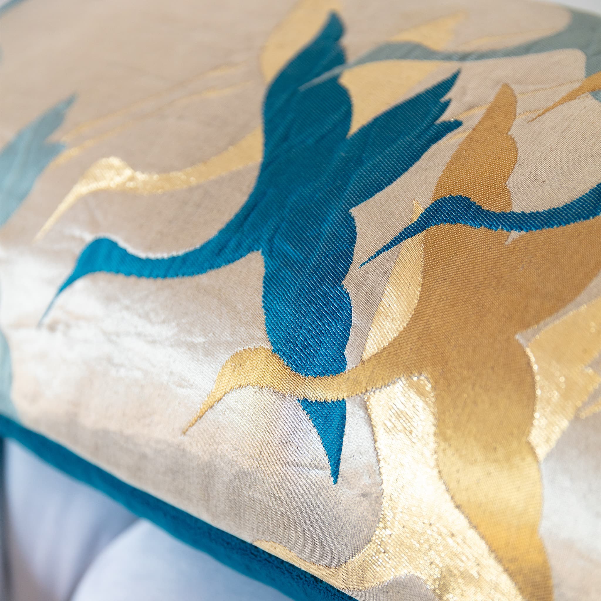 Decorative pillow with blue and gold crane bird embroidery on a pale gold background