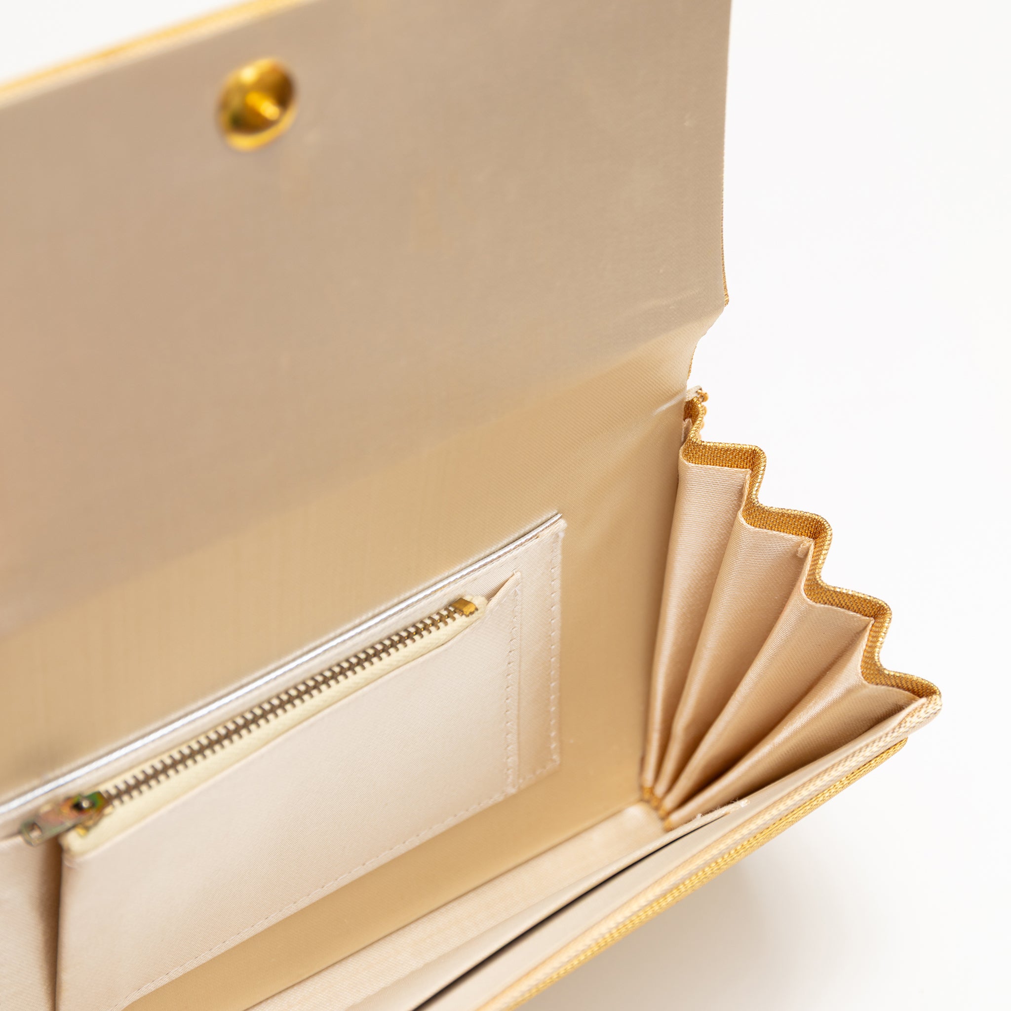 View looking inside a vintage Japanese gold clutch bag showing an interior pocket with zip fastening.