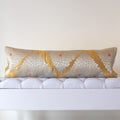 Long gold silk bolster cushion with silver chrysanthemum motifs on white upholstered bench