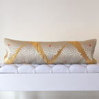 Long gold silk bolster cushion with silver chrysanthemum motifs on white upholstered bench