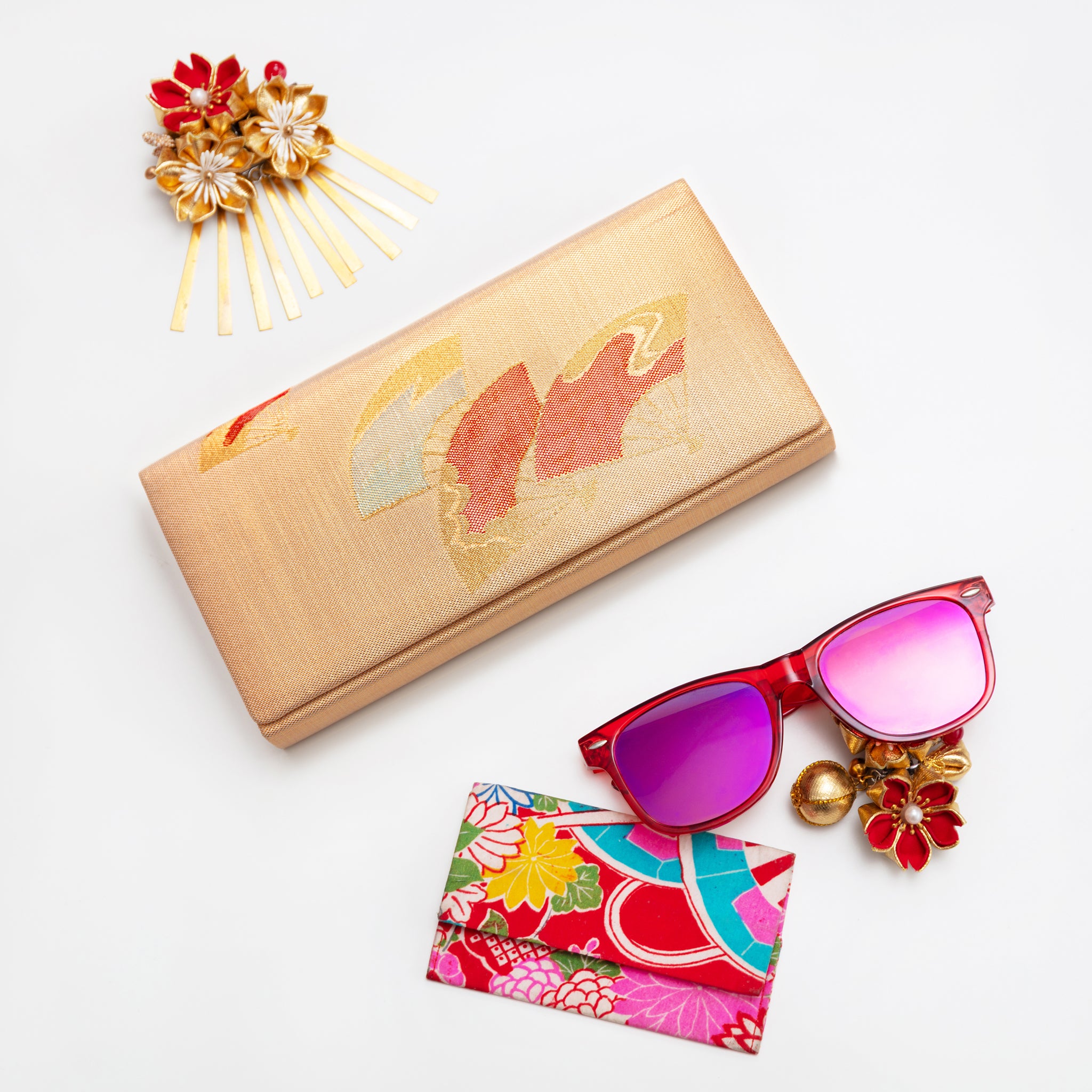 Metallic gold vintage silk clutch bag from Japan with red fans design, surrounded by accessories on a white background.