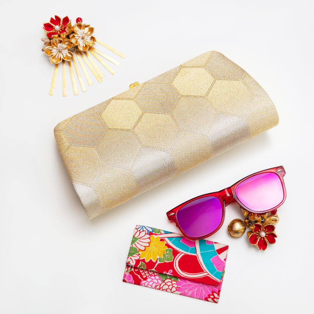 Vintage Japanese silk clutch bag in metallic gold with fortune hexagon pattern, with accessories on white background