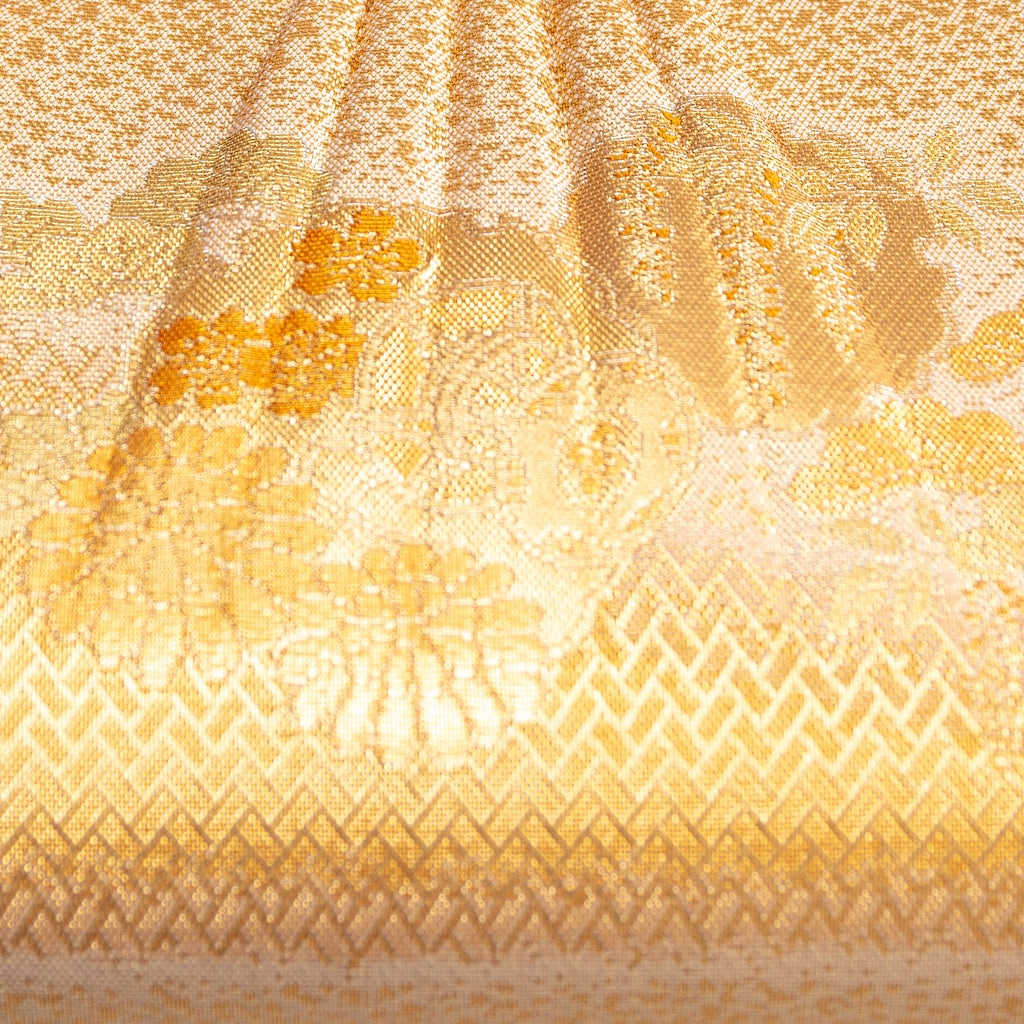 Close up of vintage Japanese silk clutch bag in metallic gold with floral, basketweave and genji wheel patterns.