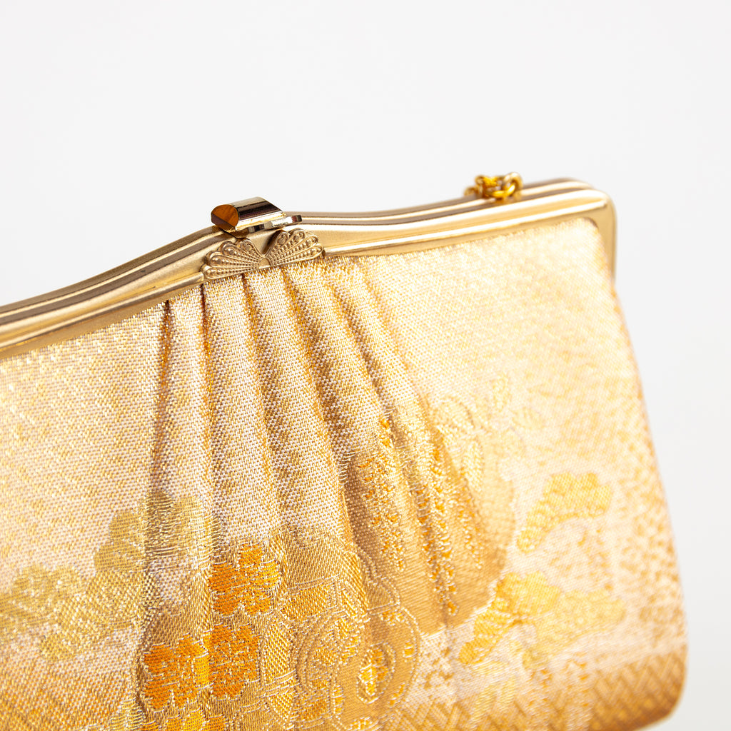 Detail of vintage Japanese silk clutch bag in gold showing decorative metal clasp closure and frame.