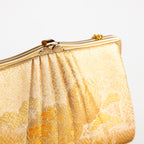 Detail of vintage Japanese silk clutch bag in gold showing decorative metal clasp closure and frame.