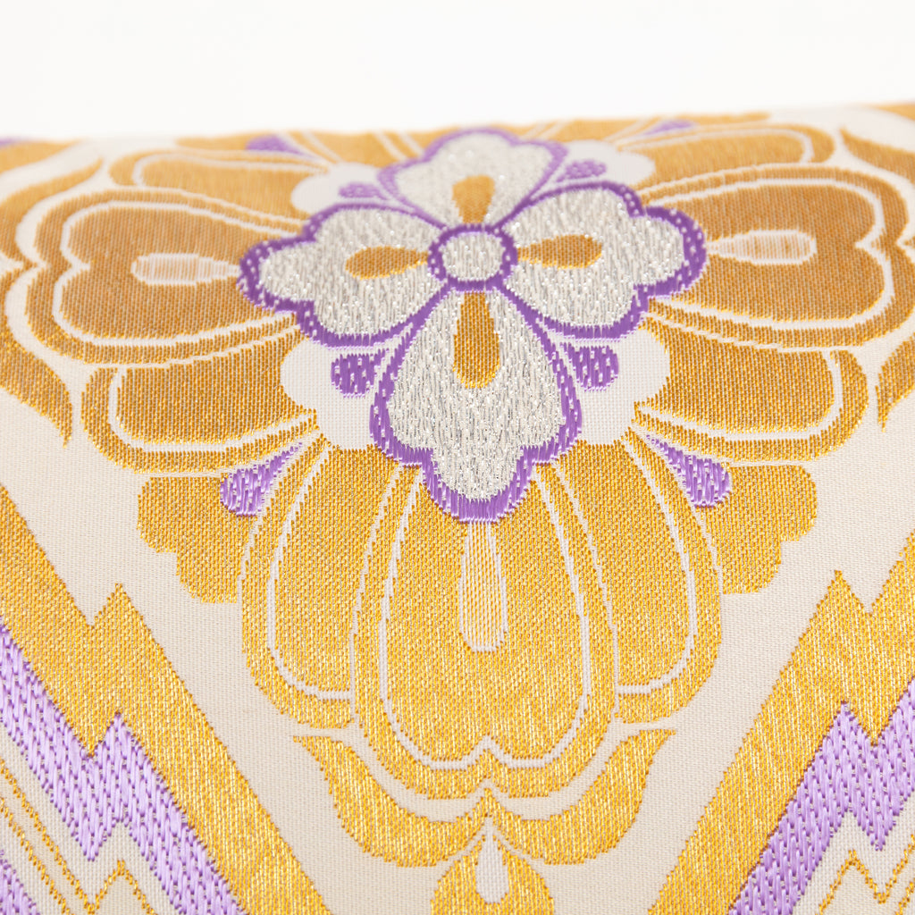 Detail of metallic gold embroidery and purple silk thread weaving on a vintage Japanese obi cushion.