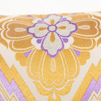 Detail of metallic gold embroidery and purple silk thread weaving on a vintage Japanese obi cushion.